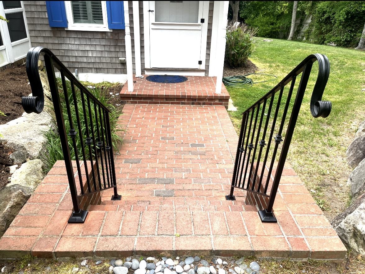 Pair of finished custom black metal handrails on brick steps