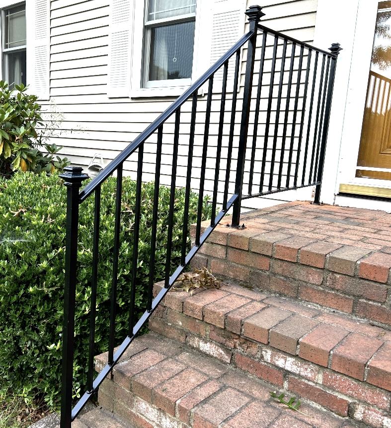 Finished black metal railing installed beside brick steps