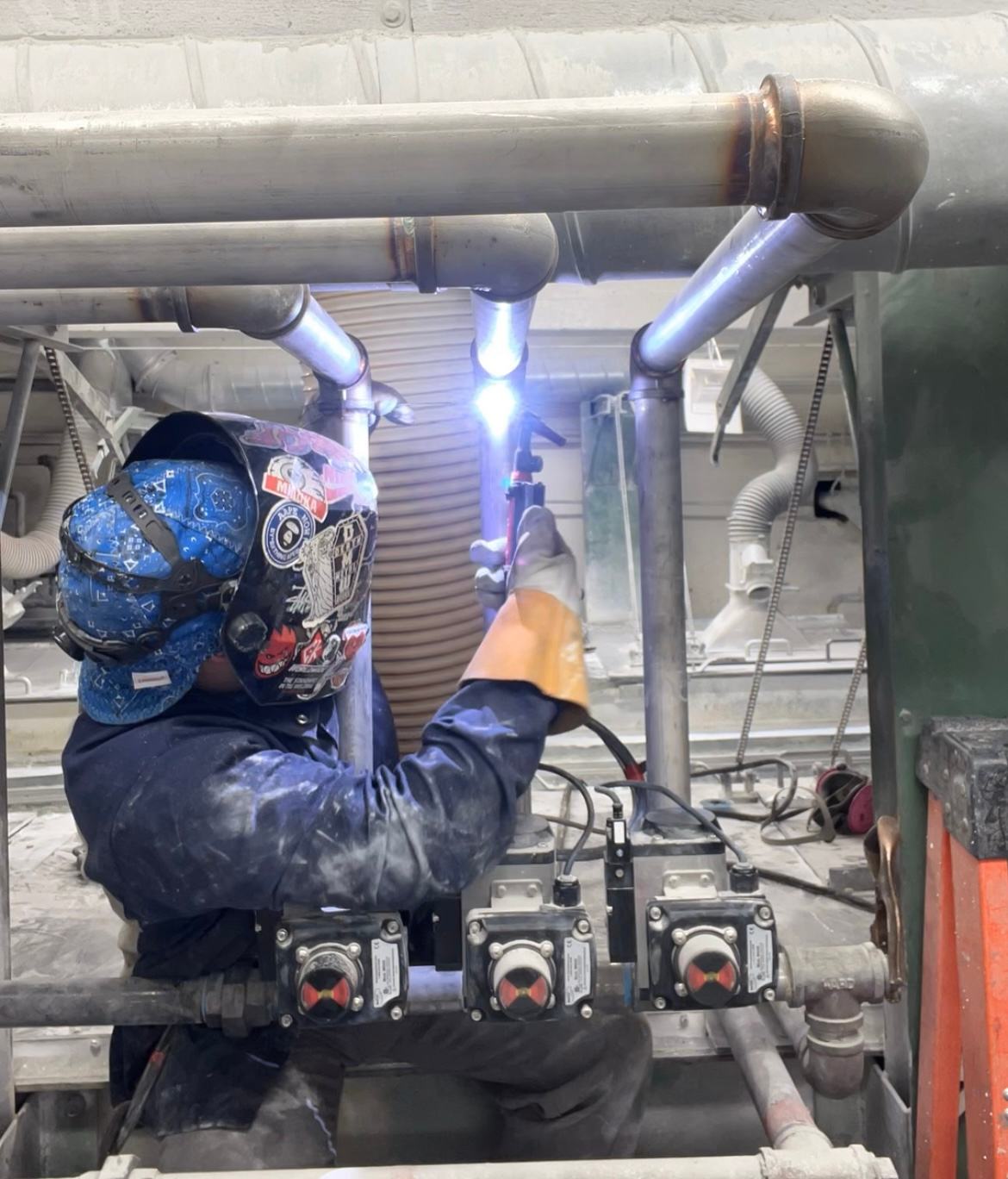 Welder completing work on an industrial pipe system
