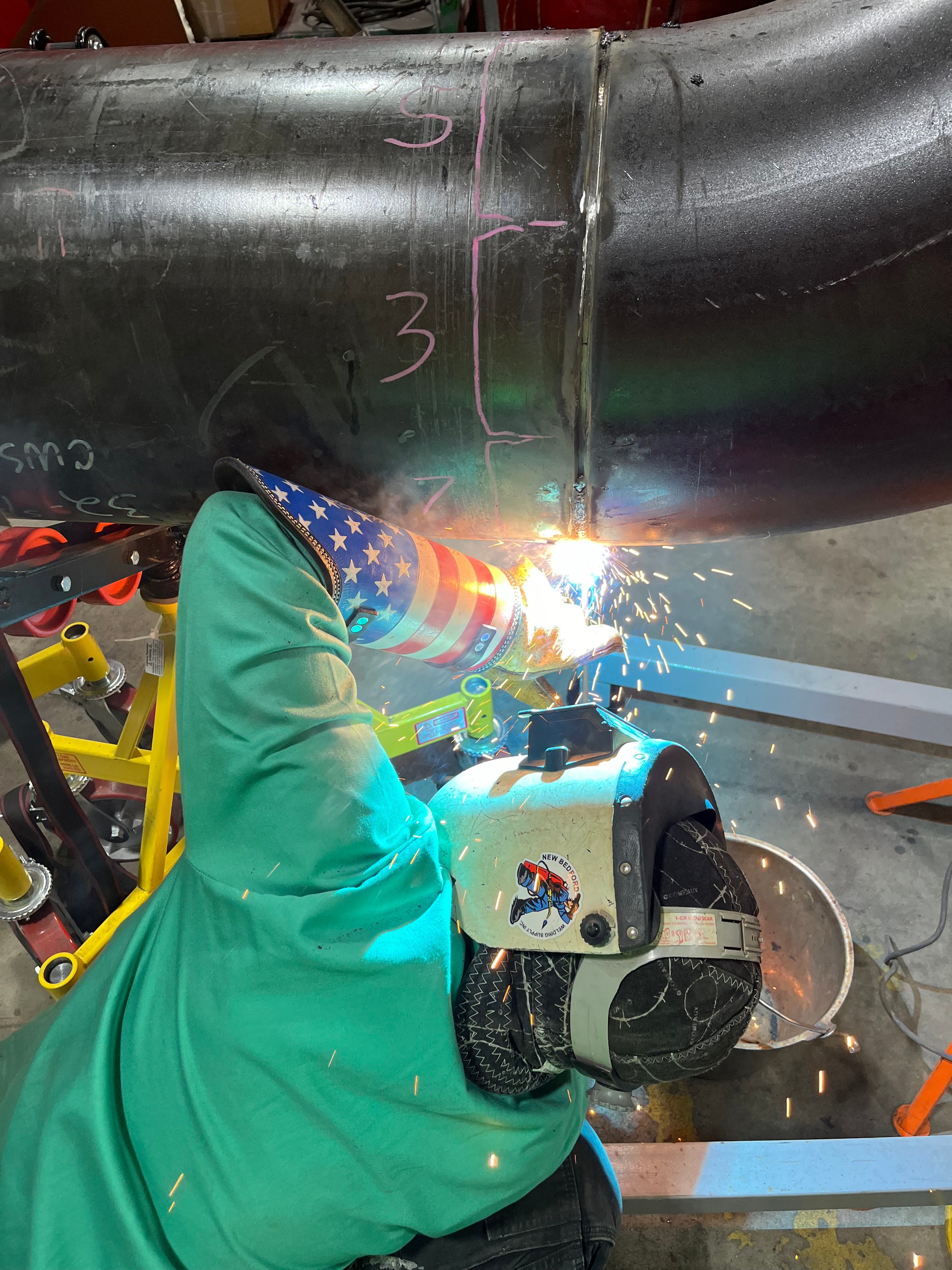 Welder joining a large carbon steel pipe section